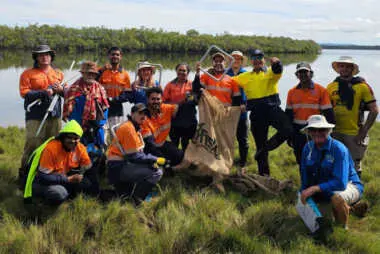 A group of people in high vis gear posing for the camera in front of a wetland
