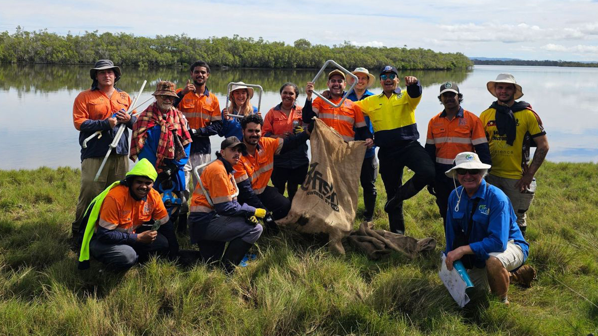 A group of people in high vis gear posing for the camera in front of a wetland