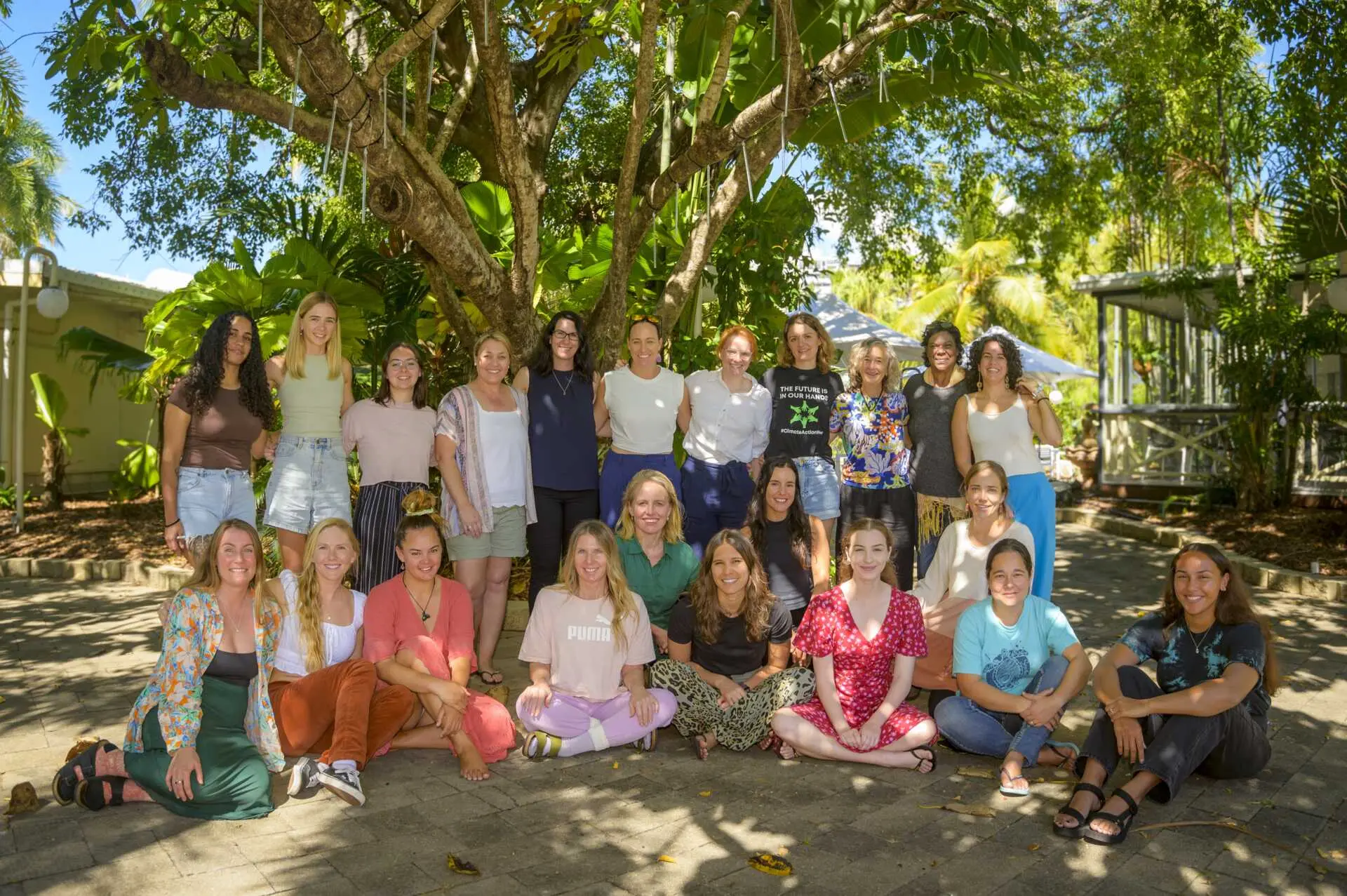 A group of young women at the Women’s Environmental Leadership Australia (WELA) Great Barrier Reef Leadership Intensive posing for a picture outside under a large tree