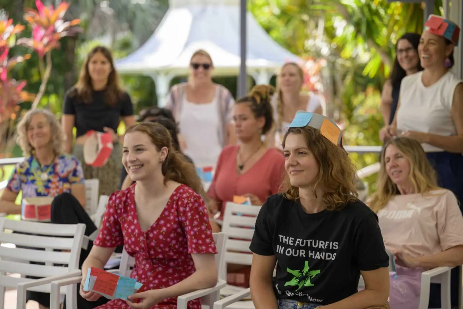 Two young women smiling in a crowd watching a presentation happening off screen at the Women’s Environmental Leadership Australia (WELA) Great Barrier Reef Leadership Intensive